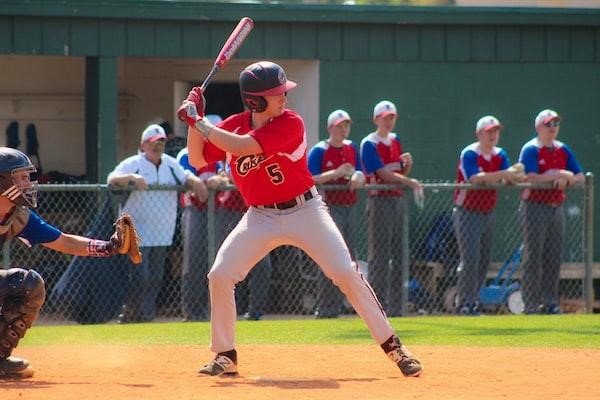 A batter in a red jersey prepares to utilize the skills they learned in baseball training during a game