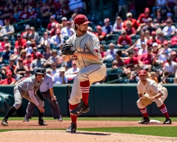 A pitcher in a grey and red uniform prepares to throw a pitch during a professional baseball game