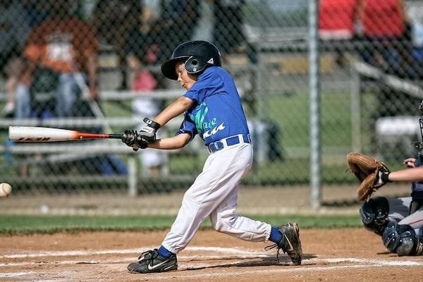 A young boy in a blue jersey and white pants swings a bat during a baseball game.