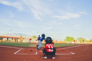 Young baseball player swings the bat, shot from behind the catcher